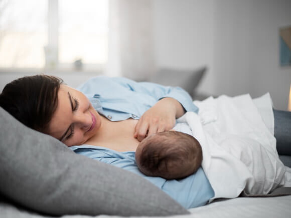 mulher amamentando um bebê enquanto está deitada
