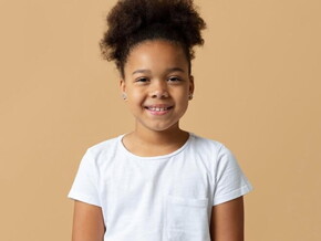 Menina com cabelo preso e camiseta branca sorrindo