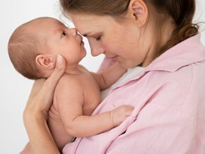Mulher segurando seu bebê recém-nascido no colo, compartilhando um momento de ternura entre mãe e filho