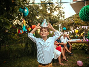 menino sorridente colocando chapéu de aniversário em festa de criança