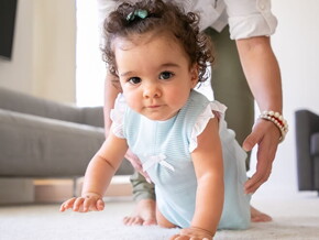 Menina vestindo vestido azul aprendendo a engatinhar