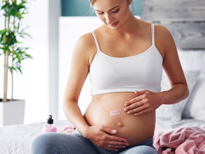 gestante sentada passando creme na barriga