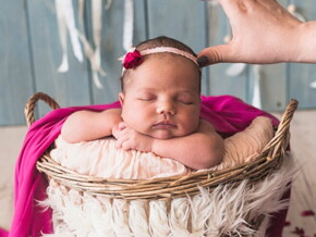 Fotógrafa ajustado adereço na cabeça de uma bebê recém nascida no ensaio fotográfico. 