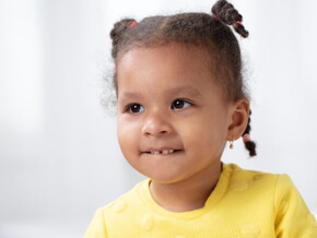 Menina vestindo blusa amarela e usando tranças no cabelo