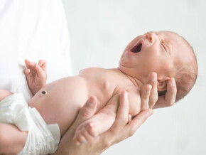 Bebê recém nascido bocejando nos braços do pai.