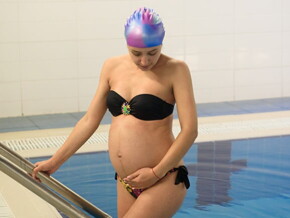 Mulher grávida saindo de uma piscina após aula de hidroterapia