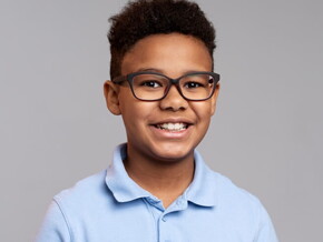 Menino vestindo camisa azul e usando óculos, sorrindo