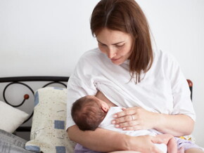 mãe amamenta bebê sentada em cama