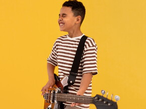 Menino usando camiseta listrada tocando guitarra.