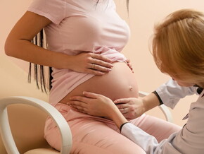 Médica obstetra apalpando a barriga de uma mulher grávida