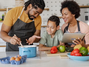 homem e mulher com uma criança ao meio cozinham sorridentes