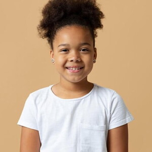 Menina com cabelo preso e camiseta branca sorrindo