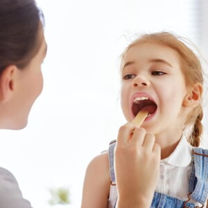 uma médica examinando a boca de uma menina criança