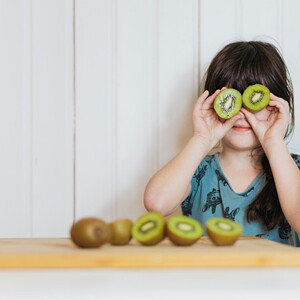 menina segurando duas rodelas de kiwi