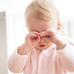 Bebê com as mãozinhas sobre os olhos