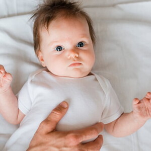 Bebê deitado em uma cama recebendo cuidados de uma profissional de saúde