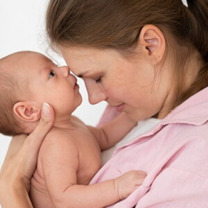 Mãe segurando a filha recém nascida no colo e com os rostos juntos.