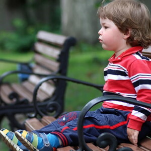 Criança sentada em um banco com as pernas estendidas