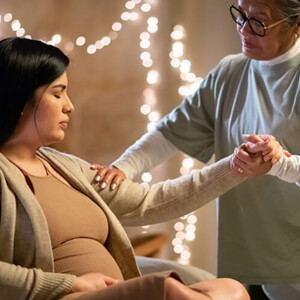 Doula segurando a mão de uma mulher grávida em trabalho de parto, demonstrando apoio e conexão