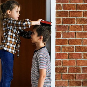 Duas crianças em frente um parede de tijolos brincando de medir a altura