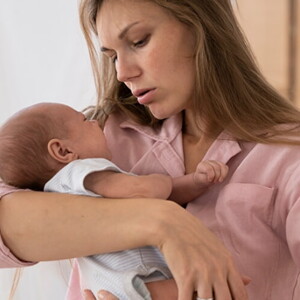 Mulher com blusa rosa carregando o recém-nascido no colo