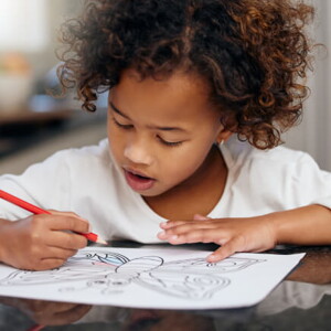 menina debruçada sobre mesa fazendo desenho