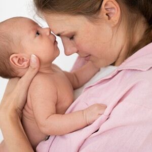 Mulher segurando seu bebê recém-nascido no colo, compartilhando um momento de ternura entre mãe e filho