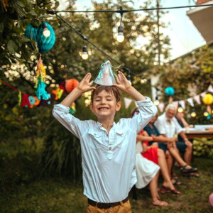 menino sorridente colocando chapéu de aniversário em festa de criança