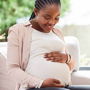 gestante sentada com as mãos na barriga