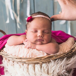 Fotógrafa ajustado adereço na cabeça de uma bebê recém nascida no ensaio fotográfico. 