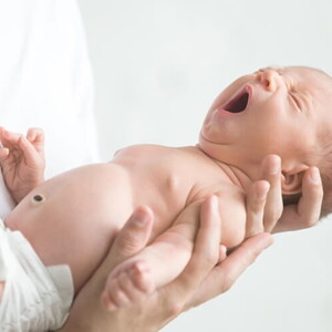 Bebê recém nascido bocejando nos braços do pai.