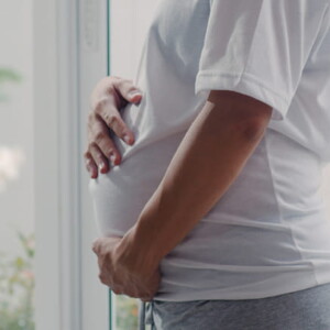 imagem de uma mulher grávida usando uma camiseta branco, com maior foco na barriga