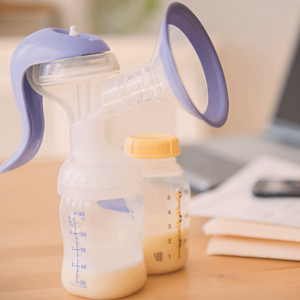 Partially filled breastmilk pump standing next to an also partially fill breastmilk bottle.