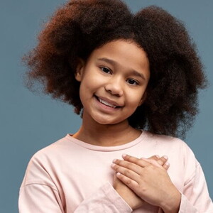 Menina usando vestido de princesa e tiara clara em frente a um fundo azul claro