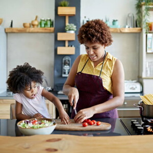 mulher pica legumes sob mesa de cozinha com criança ao lado interagindo