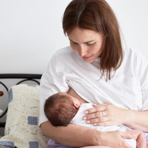 mãe amamenta bebê sentada em cama