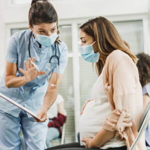 médica dialogando com uma gestante e mostrando uma prancheta