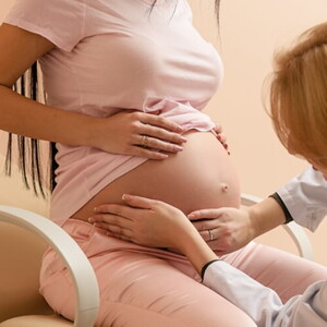 Médica obstetra apalpando a barriga de uma mulher grávida