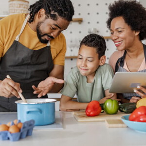 homem e mulher com uma criança ao meio cozinham sorridentes