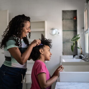 mulher faz tranças no cabelo de criança