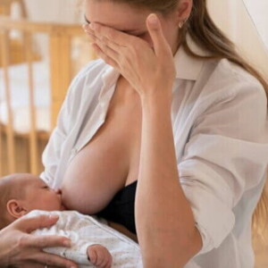 Mulher amamentando bebê recém-nascido com expressão preocupada