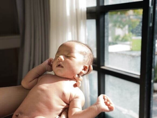 Bebê tomando banho de sol através da luz de uma janela