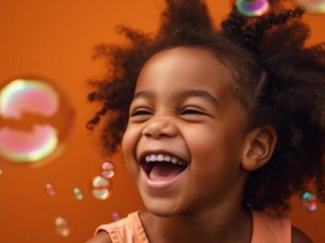 Menina sorrindo alegremente com bolhas de sabão em frente uma parede colorida