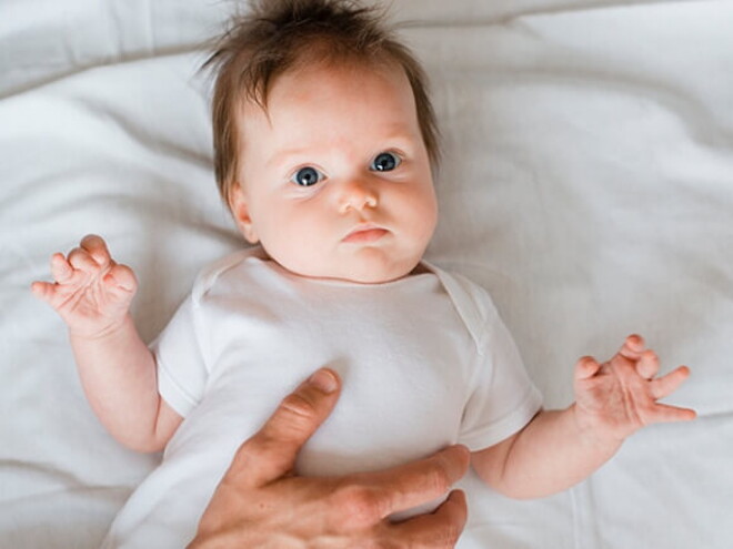 Bebê deitado em uma cama recebendo cuidados de uma profissional de saúde