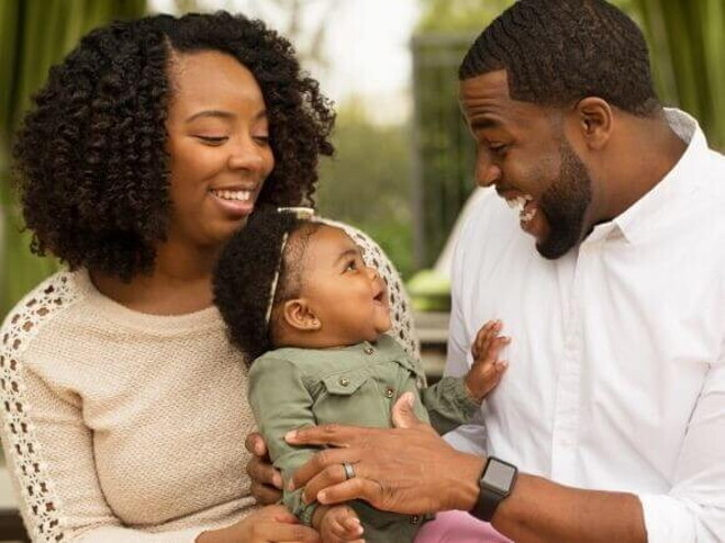 Mãe e pai sorrindo com o bebê no colo