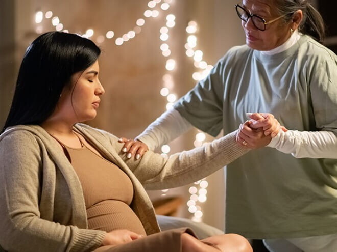 Doula segurando a mão de uma mulher grávida em trabalho de parto, demonstrando apoio e conexão