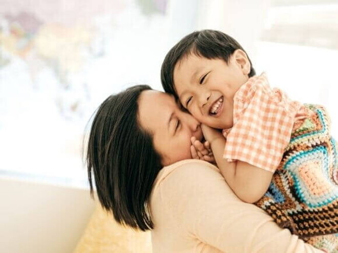 Uma mãe segurando o filho nos braços e sorrindo