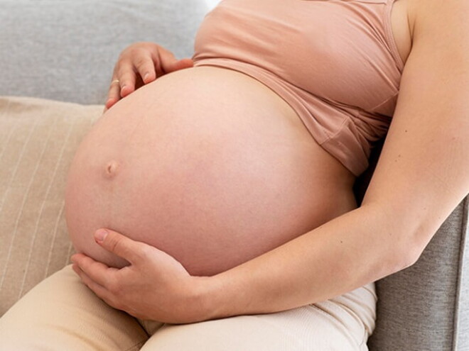 Gestante sentada com a mão na barriga