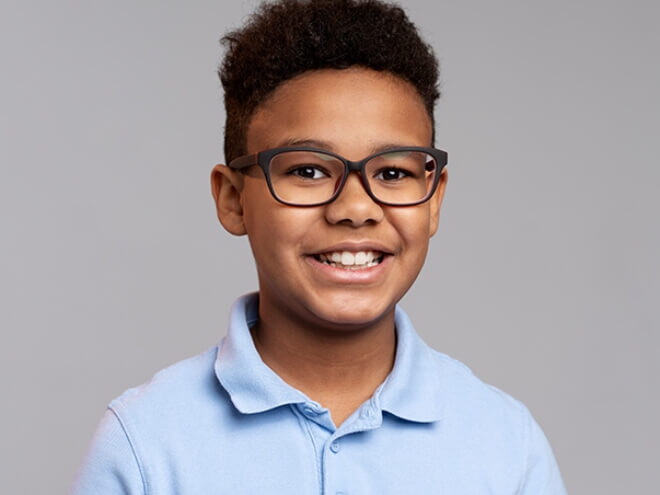 Menino vestindo camisa azul e usando óculos, sorrindo