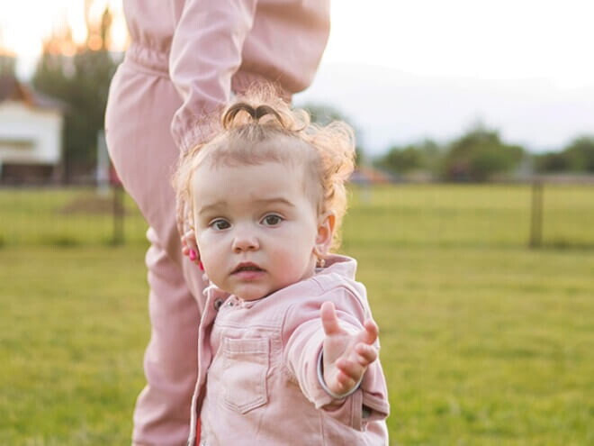 Mãe andando com sua filha pequena em uma fazenda.